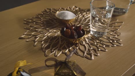 bowl of dates with glass of water on table in muslim home celebrating eid