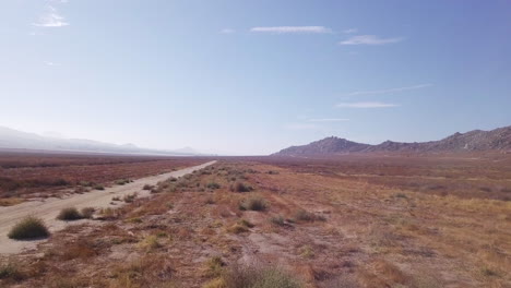 Backwards-Drone-Footage-Of-Dusty-Road-In-the-Desert-In-California