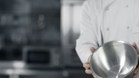 las manos del chef se divierten con el cuenco de acero en cámara lenta. el chef se prepara para cocinar.