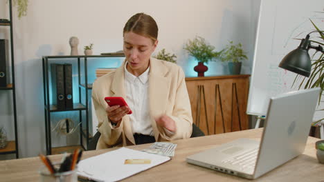 Mujer-De-Negocios-Rica,-Chica-Que-Trabaja-En-Un-Teléfono-Inteligente-Contando-Dinero-En-Efectivo,-Calcula-Ganancias,-Ingresos-Y-Ganancias.