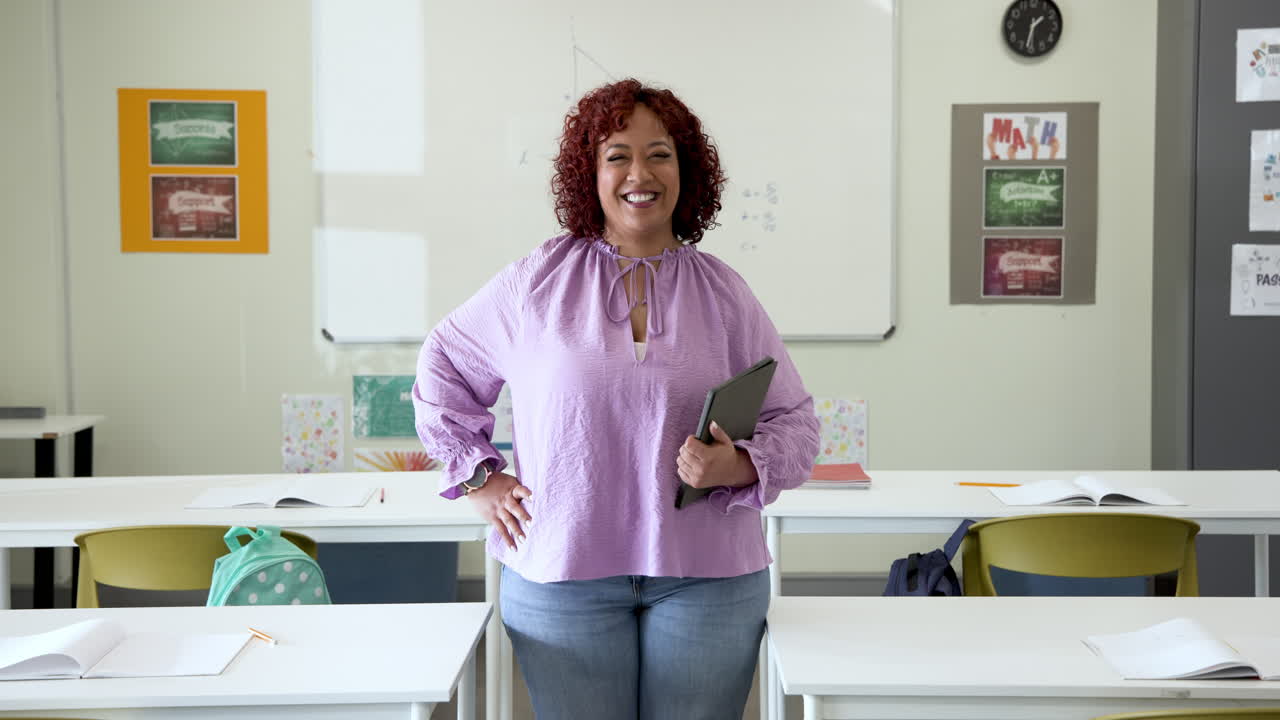In school, female teacher holding tablet preparing for lesson in classroom