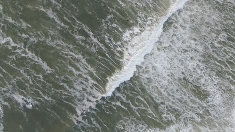 Top-down-view-of-the-ocean-and-some-surfers-in-the-evening