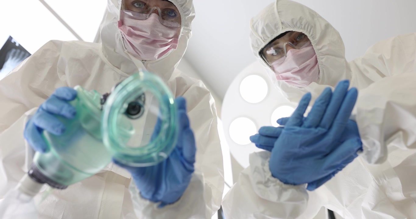 Medici in tute protettive preparano la maschera per l'anestesia prima dell'intervento chirurgico.