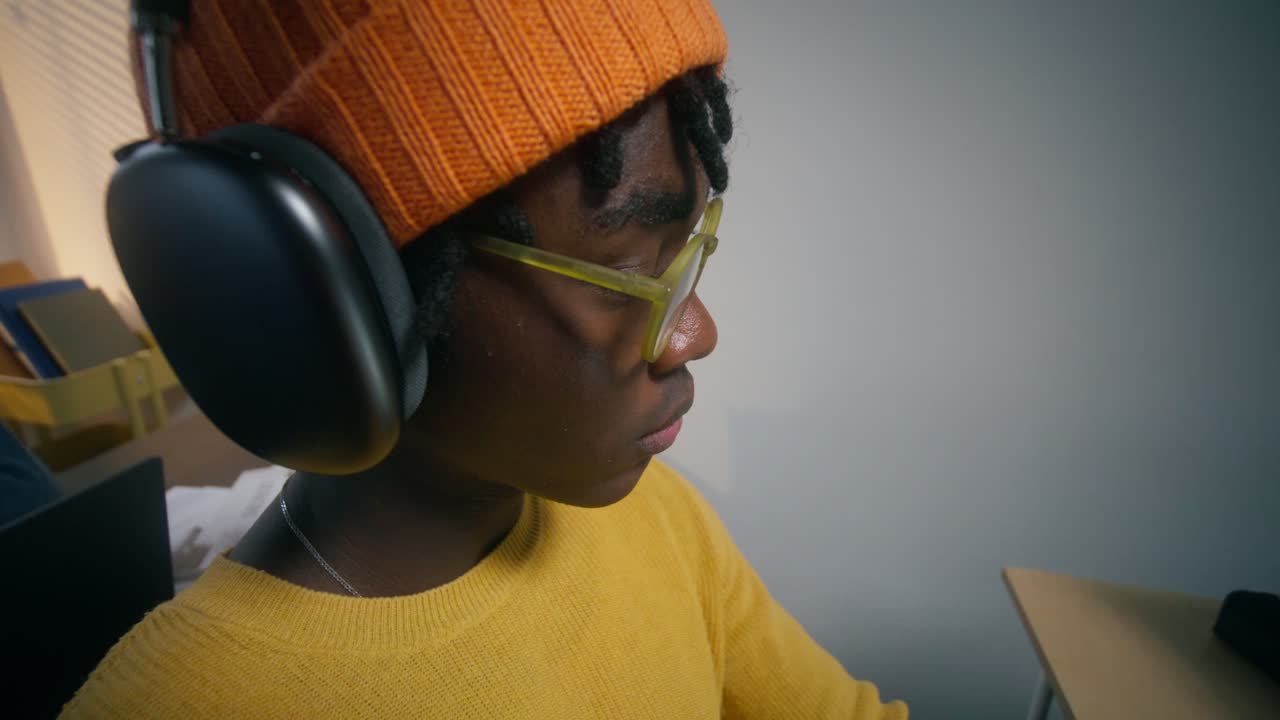 un adolescente estudiando con auriculares