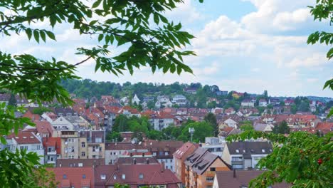 pan on city of stuttgart, green trees in foreground and cumulus clouds in the sky