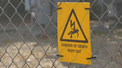 yellow danger of death sign on a chainlink fence