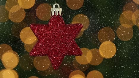 Animation-of-snow-falling-over-red-star-christmas-bauble-decoration