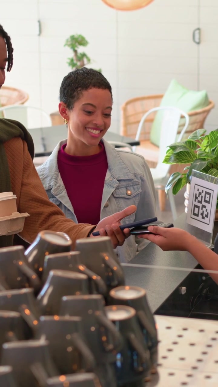 Vertical video: Receiving woman taking takeaway in cafe as staff hands box, finishing phone payment