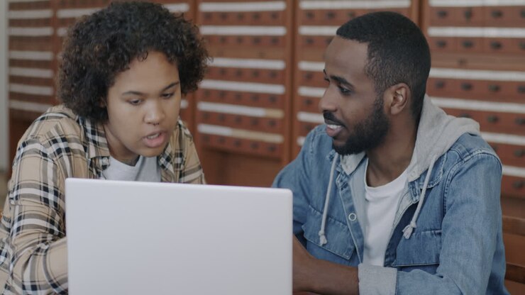 Two people discussing something on a laptop in a library