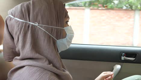 woman in hijab and mask in a car