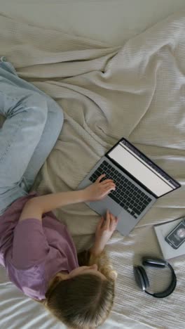 woman working on laptop on bed