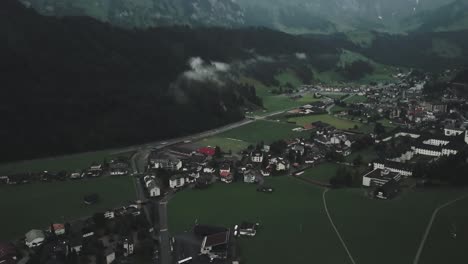 Drone-aerial-from-mountains-to-reveal-small-quiet-town-in-Switzerland-in-green-lands