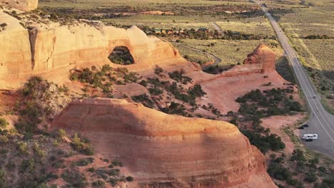 Aerial-view-of-Wilson-Arch-in-southeastern-Utah,-USA,-capturing-the-majestic-landscape-during-sunset