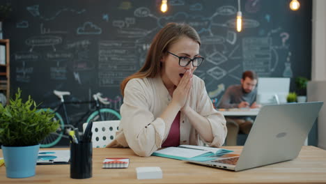 woman excitedly working on laptop in office