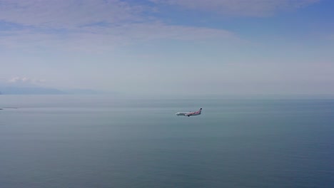 passenger airplane flying over black sea expanse and touching down at the airport among batumi morning cityscape