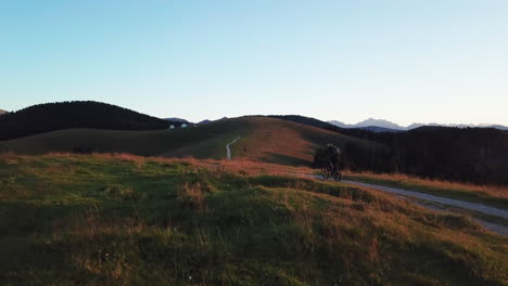 Aerial-following-shot-of-mountain-biker-cycling-through-rural-countryside