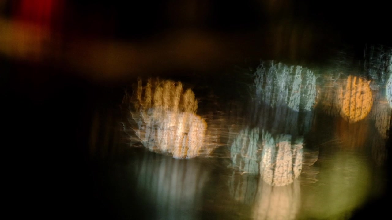 Out of focus car headlights seen through a wet window in the rain