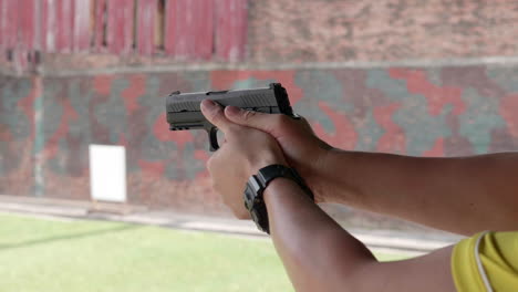 slow motion scenes of the gun firing at a shooting range on the man hand withhold the gun tight and pull the trigger