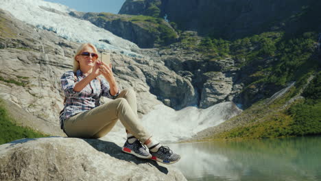 a happy tourist does selfie on the background of a glacier in norway traveling in norway concept