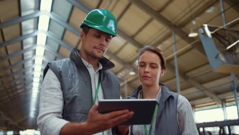 Livestock-workers-using-tablet-device-in-cowshed.-Dairy-farm-professionals.