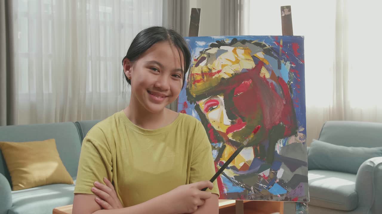 Asian Artist Girl Holding Paintbrush Crossing His Arm And Smiling After Finish Painting A Girl On The Canvas
