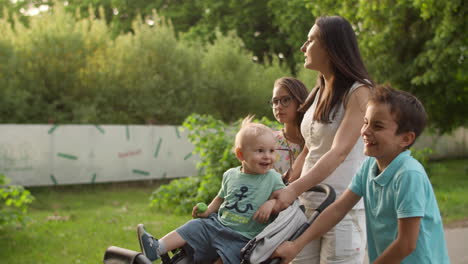 Entspannte-Mutter-Geht-Mit-Drei-Kindern-Spazieren.-Glückliche-Familie,-Die-Sich-Im-Sommerpark-Entspannt