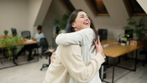 Young-female-office-workers-hugging-to-congratulate-a-colleague-or-missing-a-friend-from-vacation