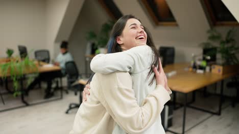 jóvenes trabajadoras de oficina abrazando para felicitar a un colega o extrañando a un amigo de vacaciones