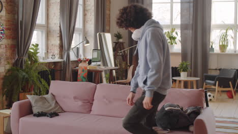 teenage boy playing console at home after school