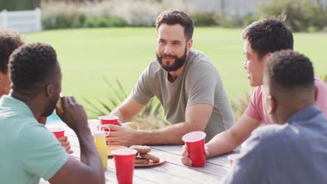 Happy-diverse-male-friends-sitting-at-table-laughing,-eating-and-drinking