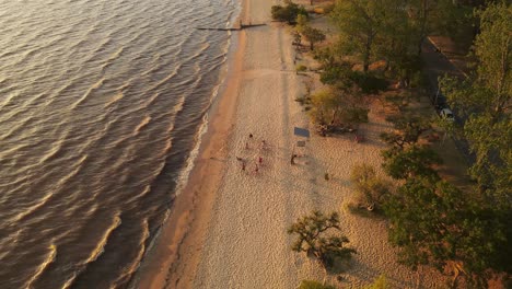 Luftaufnahme-Von-Oben-Nach-Unten,-Die-Eine-Gruppe-Junger-Teenager-Zeigt,-Die-Bei-Sonnenuntergang-Beachvolleyball-Spielen-–-Nach-Unten-Geneigt