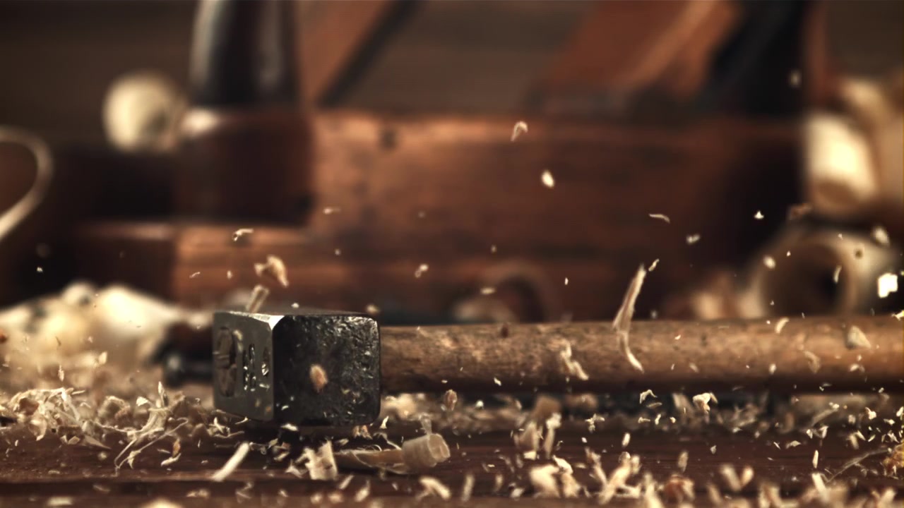 Hammer Falling onto Wooden Workbench with Scattering Wood Shavings in Slow Motion