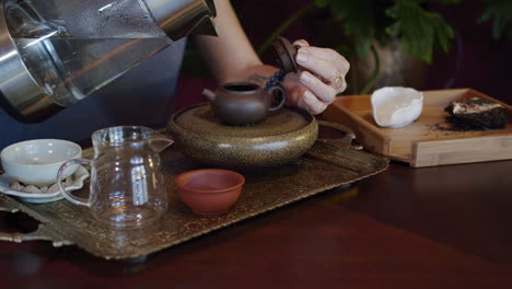 woman-pours-tea-from-clay-teapot-into-pitcher,-then-into-clay-teacup