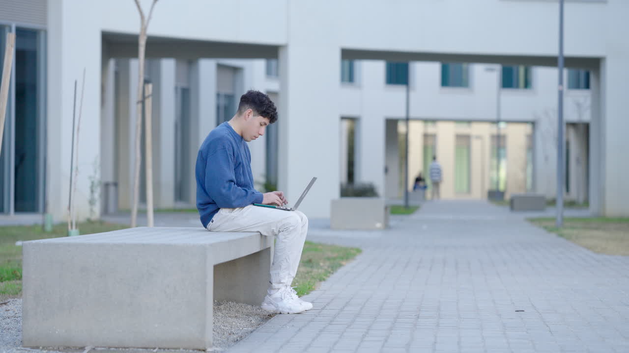 Student working on laptop outside university building