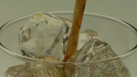 el líquido de color ámbar se vierte sobre hielo en un vaso