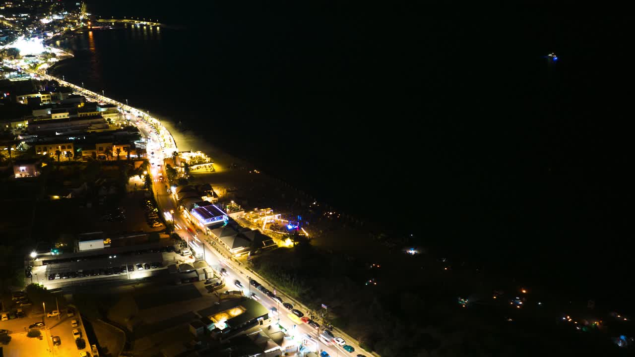 Dynamic 4K timelapse of the sea at night, with moving car lights along the coastal road