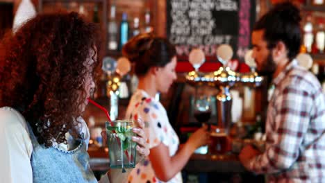 beautiful woman looking at couple while having cocktail