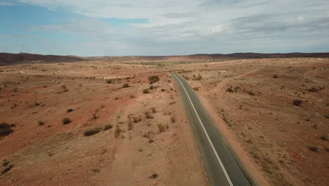 aerial: drone shot flying over a solo highway in a rugged, empty, desert environment near broken hill australia