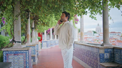 handsome guy calling cellphone at city view balcony. tanned macho talking phone