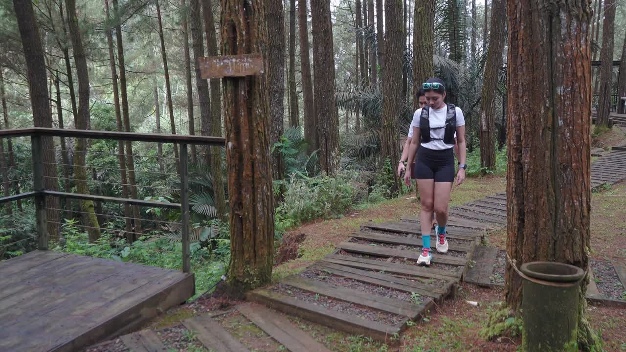 Asian couple walking on forest trail path during outdoor adventure in Indonesia