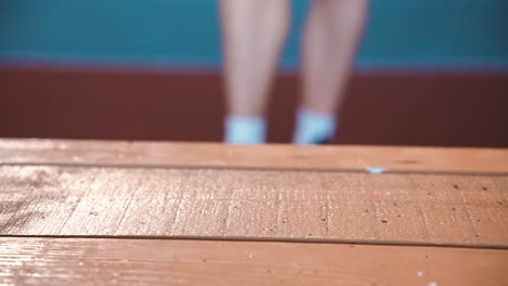 primer plano de una deportista rubia enfocada calentando y estirando las piernas en una instalación deportiva cubierta