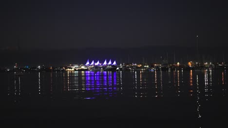 illuminated structures reflecting on calm lake at night