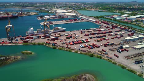 órbita aérea panorámica de un contenedor marítimo atracado en un puerto descargando carga con grúas, curacao