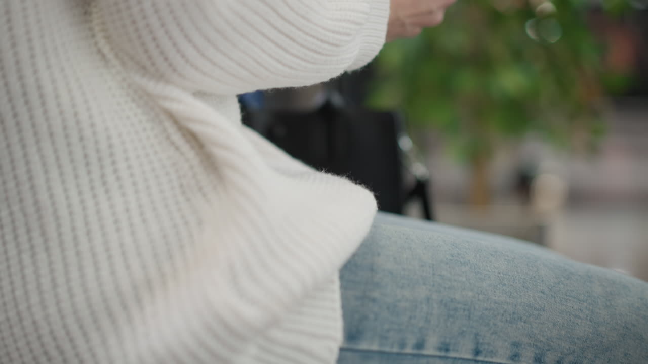 contemporary woman walking to seat on bench in upscale mall interior holding bag, slow steps to bench, closeup of legs and bag strap, muted colors and polished floor reflecting ambient lights
