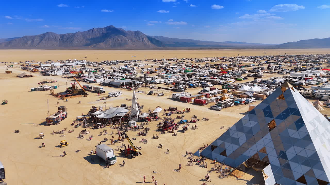 Nevada, USA, 22 August 2025: Pyramid installation and camp at Burning Man. Geometric pyramid art installation stands tall in the desert surrounded by camp and mountains