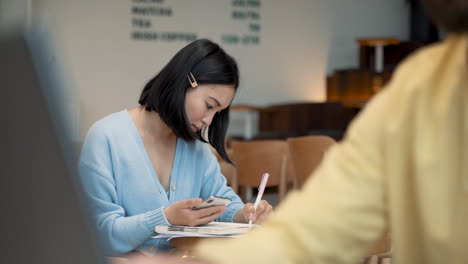 an young woman takes some notes in her notebook in a coffee shop