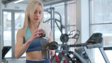 woman preparing protein shake in a gym