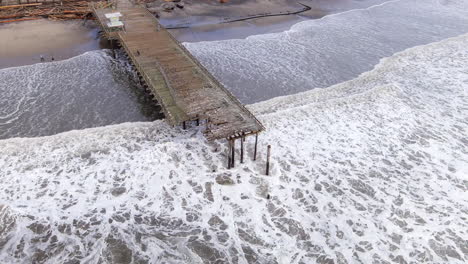 aerial, beach pier in california destroyed by a storm caused by climate change