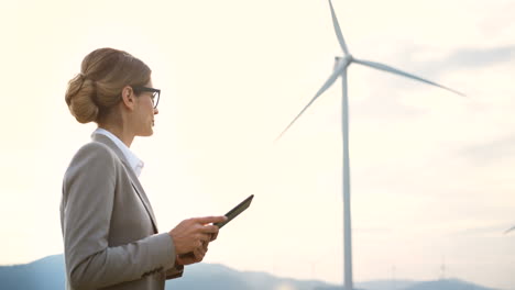 side view of caucasian woman engineer using a tablet at wind station of renewable energy