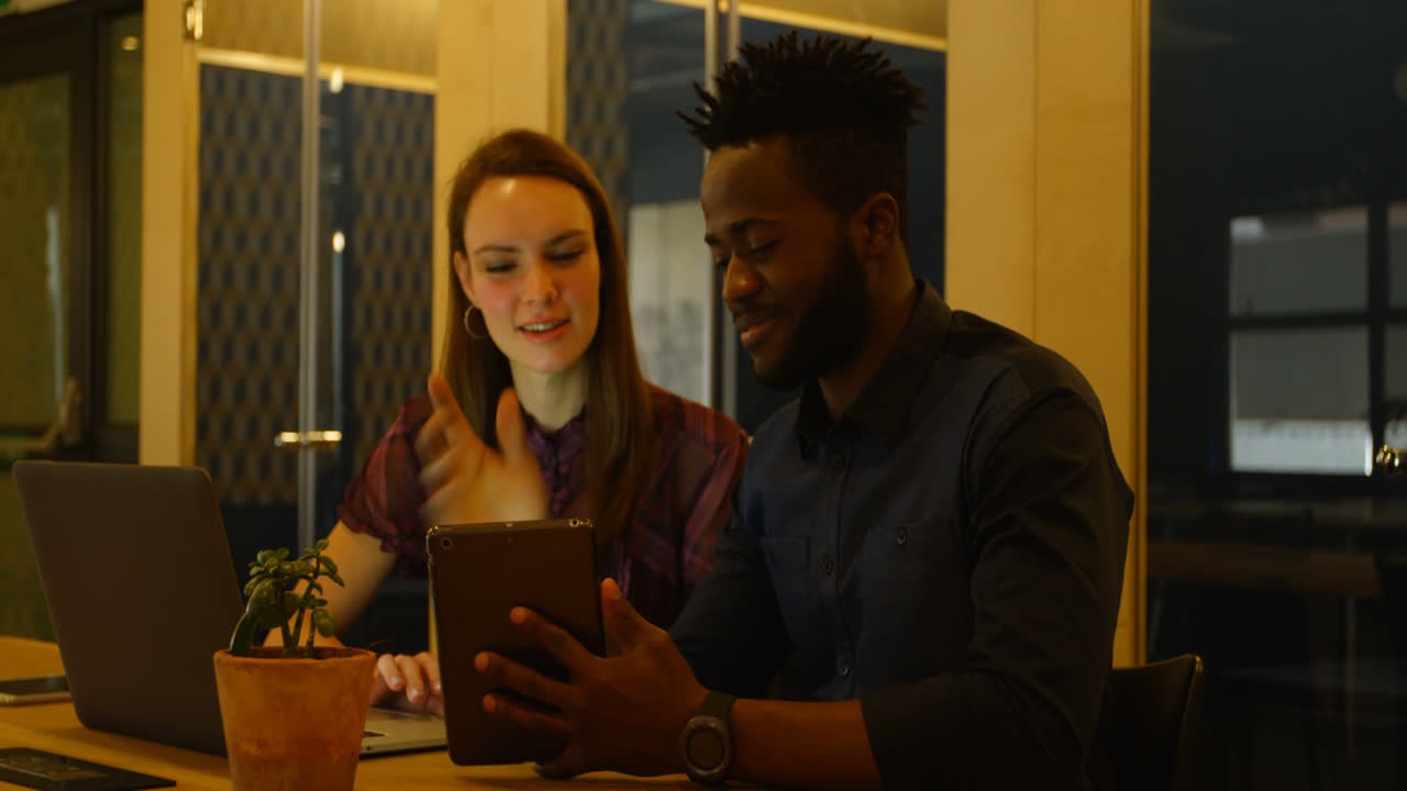 Front view of Young cool mixed-race business team planning and sitting at table of modern office 4k